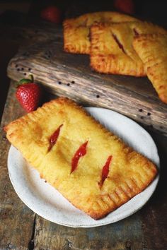 two pieces of pie on a plate with strawberries next to it and a wooden tray