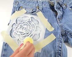 someone is cutting out paper with scissors and glue on their back pocket to make a flower