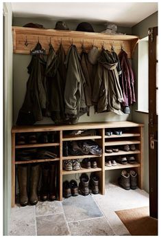 an open closet with shoes and coats hanging on the wall