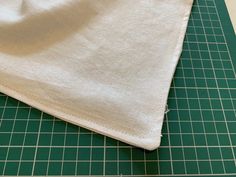 a piece of cloth sitting on top of a green cutting board next to a knife