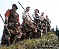 men in kilts are walking up a hill