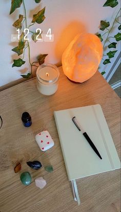 a notepad and pen sitting on top of a wooden table next to a candle