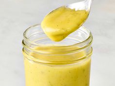 a spoon full of yellow sauce on top of a jar