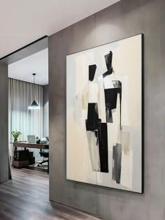 an abstract painting hangs on the wall next to a wooden floor in a living room