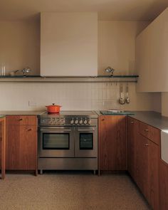 a kitchen with wooden cabinets and stainless steel stove top oven in the middle of it