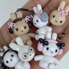 a person is holding several small key chains in their hand, some are wearing bunny ears and bow ties