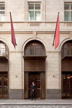 a man standing in front of a building with two red flags hanging from it's windows