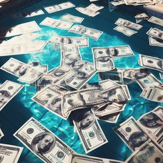 a bunch of money floating on top of a pool filled with blue water and lots of dollar bills