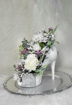 a white shoe with flowers in it sitting on a silver tray