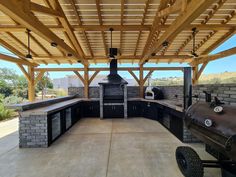 an outdoor bbq with grills and barbecue oven on the outside wall, under a pergolated roof