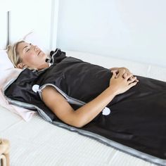 a woman laying on top of a bed with a black cover over her face and head