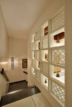 a hallway with white walls and shelves filled with bells on the wall next to a stair case