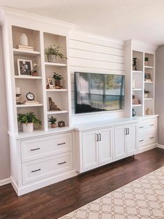 a living room with white bookcases and a flat screen tv mounted on the wall