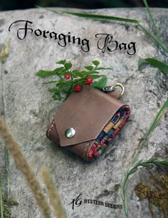 a small purse sitting on top of a rock next to some leaves and berries with the words foraging bag written below it