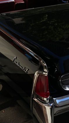 an old black car parked on the side of the road in front of another car