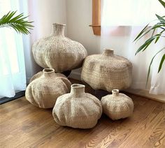 four vases sitting on the floor in front of a window