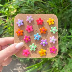 a person holding up a small wooden magnet with colorful flowers on it's side