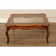 an old coffee table with glass top and wooden frame on the legs, sitting on a hard wood floor