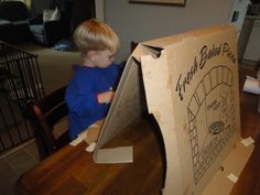 a young boy standing in front of a cardboard box