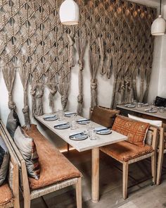 a table with place settings and chairs in front of a wall made out of rope