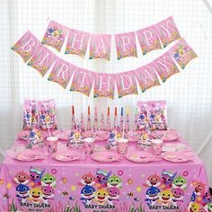 a pink birthday party table set up with decorations