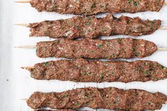 several skewered meats are lined up on a baking sheet