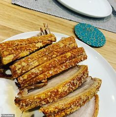 sliced meat on a white plate sitting on a wooden table