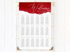 a red and white wedding seating chart hanging on a wall