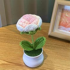 a crocheted flower sitting on top of a wooden table next to a framed photo