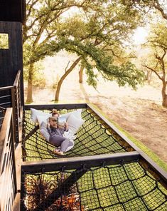 a man sitting in a hammock on top of a wooden deck next to trees