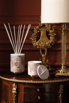 an assortment of candles, reeds and other items on a table in front of a lamp