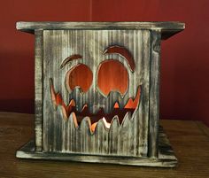 a wooden box with carved pumpkin faces on it's sides and eyes, sitting on a table