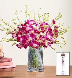 a vase filled with purple flowers sitting on top of a wooden table next to books