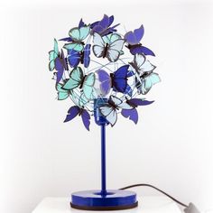 a blue lamp with butterflies on it and a cord plugged into the light bulb