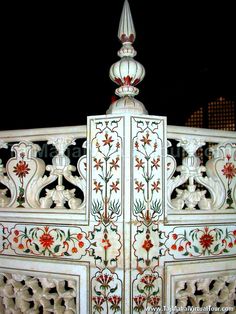 an intricately decorated white gate with red flowers on it