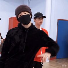 a group of young men standing around each other wearing face masks on their faces while one man in the background wears a black mask