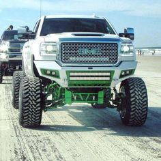 two large trucks driving down a sandy road