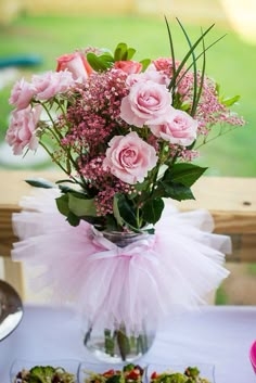 a vase filled with pink flowers sitting on top of a table next to other food