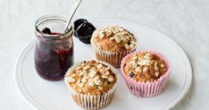 three muffins on a plate with jam and berries