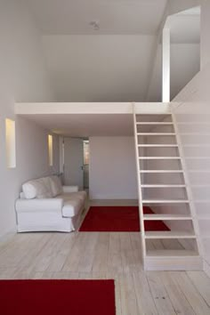 a living room with stairs leading up to the top floor and red carpet on the floor