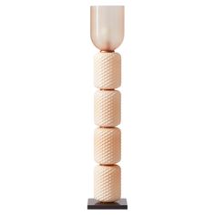 a tall white vase sitting on top of a wooden stand next to a light bulb