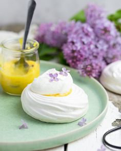 a plate topped with whipped cream next to a jar of lemonade and lila flowers