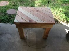 a small wooden table sitting on top of a cement floor next to a green field