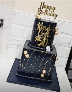 a black and gold birthday cake sitting on top of a counter