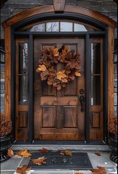 a wooden door with a wreath on it and autumn leaves in front of the door