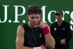 a young man holding a tennis racquet on top of a tennis court