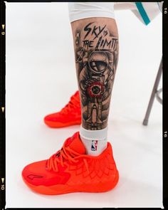 a man's legs with tattoos and basketball shoes on them, in front of a white background