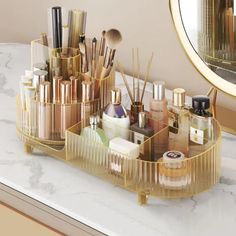 an organized makeup organizer on a marble countertop in front of a gold framed mirror