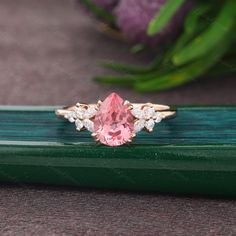 a pink diamond ring sitting on top of a green piece of wood