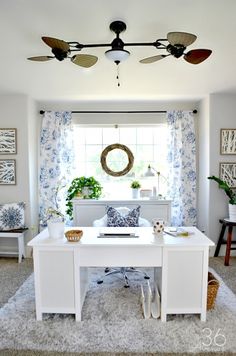 a white desk sitting in front of a window with blue and white decor on it